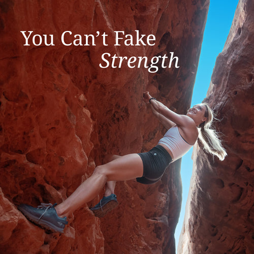 Woman in athletic wear rock climbing between red rock formations under a bright blue sky with text "You Can't Fake Strength