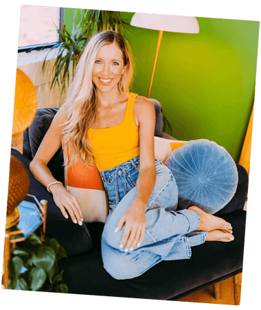Woman sitting on a couch wearing a yellow top and blue jeans in a casual setting.