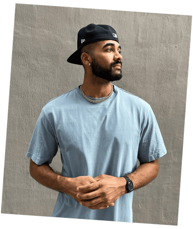 Man wearing a light blue t-shirt and black cap against a textured beige background